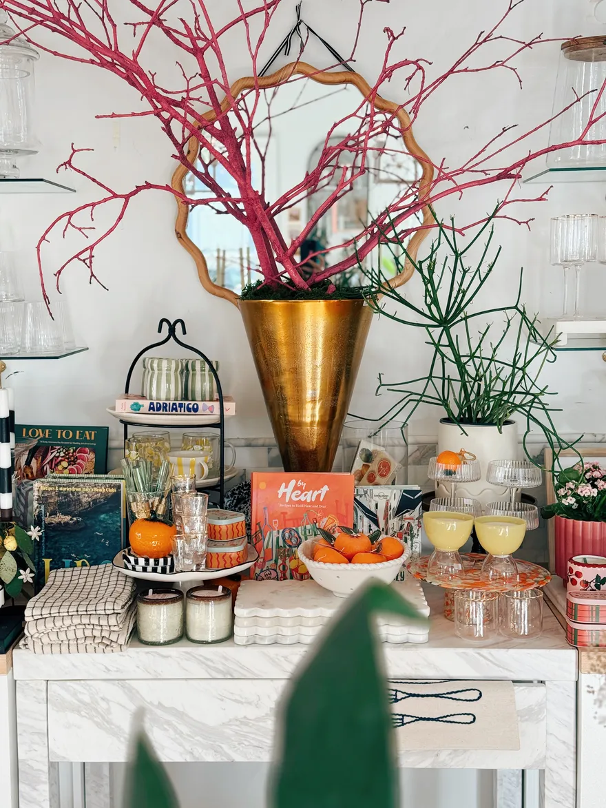 Marble console styled with cookbooks, coupe glasses, oranges and candles.