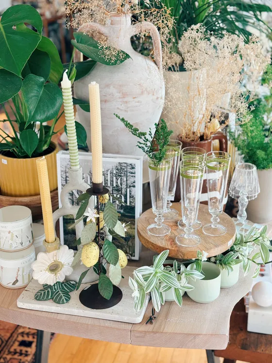 A whitewash ceramic amphora with beeswax tapers, a ceramic flower dish and green glass flutes.