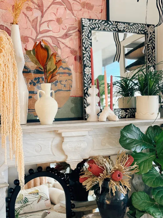 A marble mantel styled with cream amphora vases and dried florals.